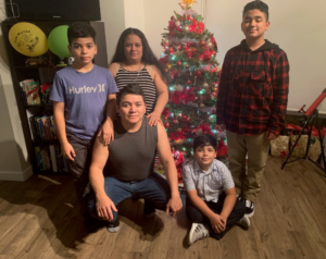 Ramon family photo at Christmas - 3 children and 2 parents by a decorated Christmas Tree.