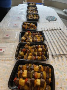 Image of a line of take away containers filled with food ready to be packed up for our Community Dinner for local families.