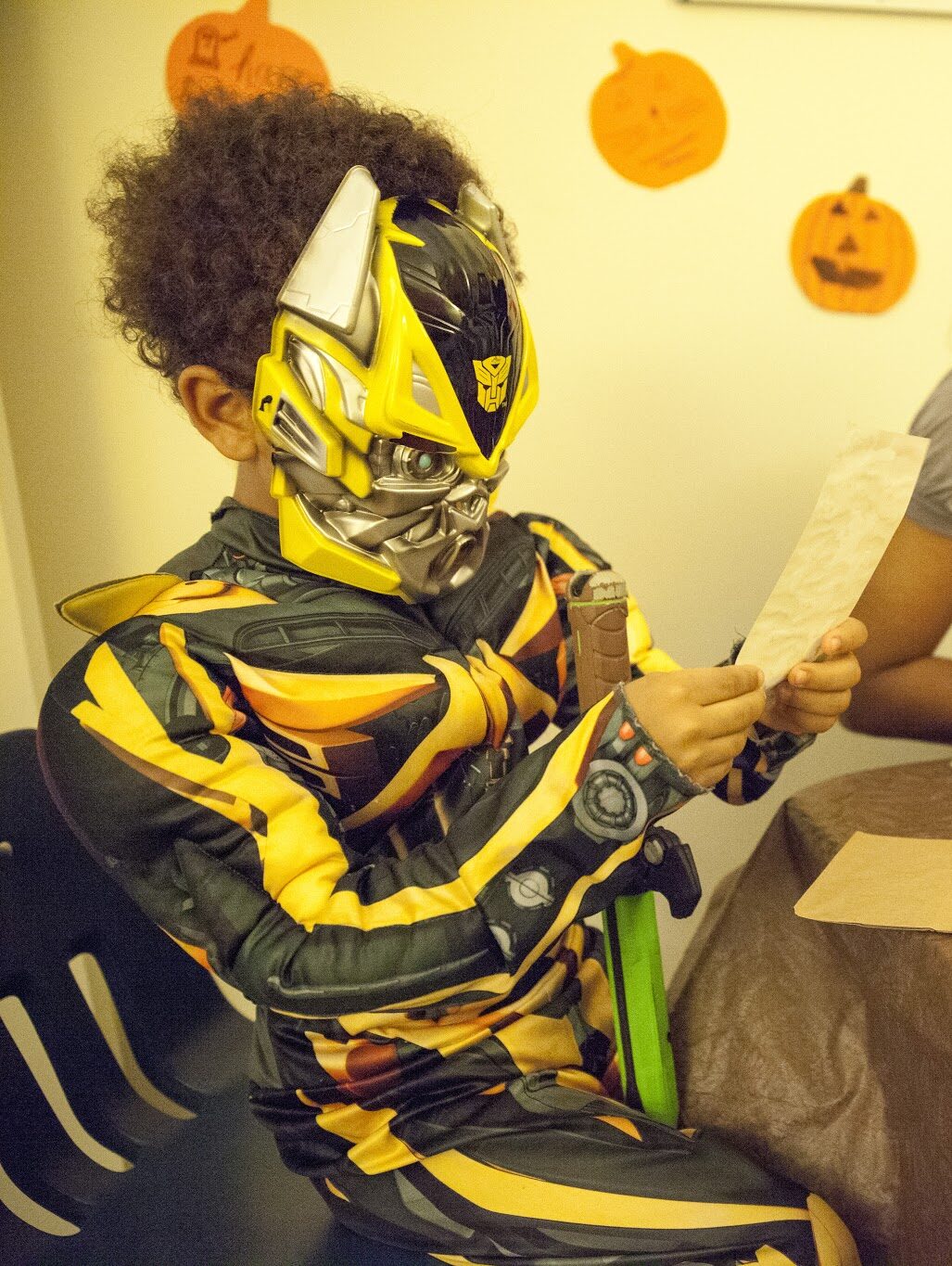 A child in halloween costume consults a piece of paper