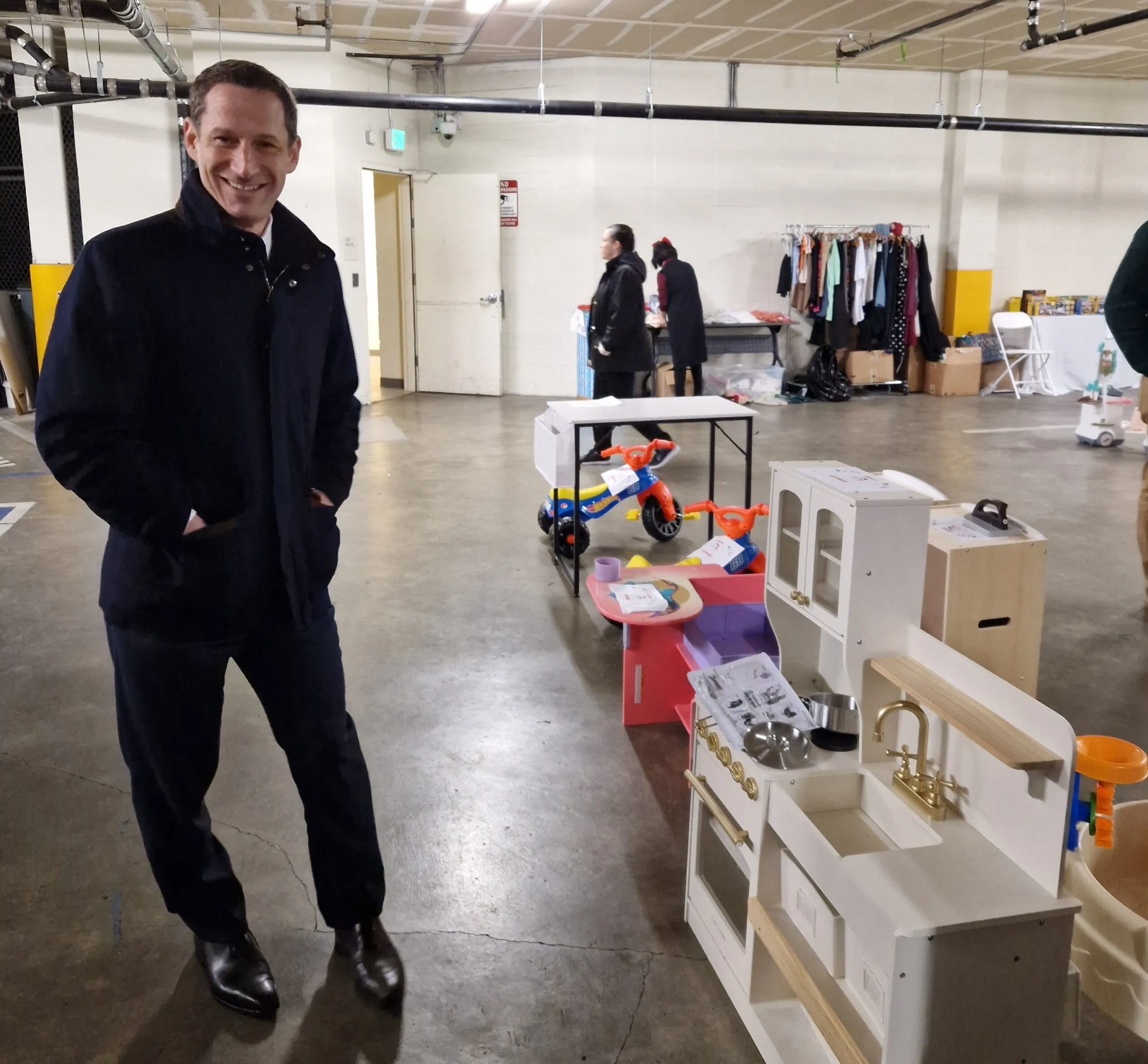 Mayor Daniel Lurie at Safe & Sound's Bayview Office garage with a toy kitchen from Safe & Sound's Holiday Toy Store