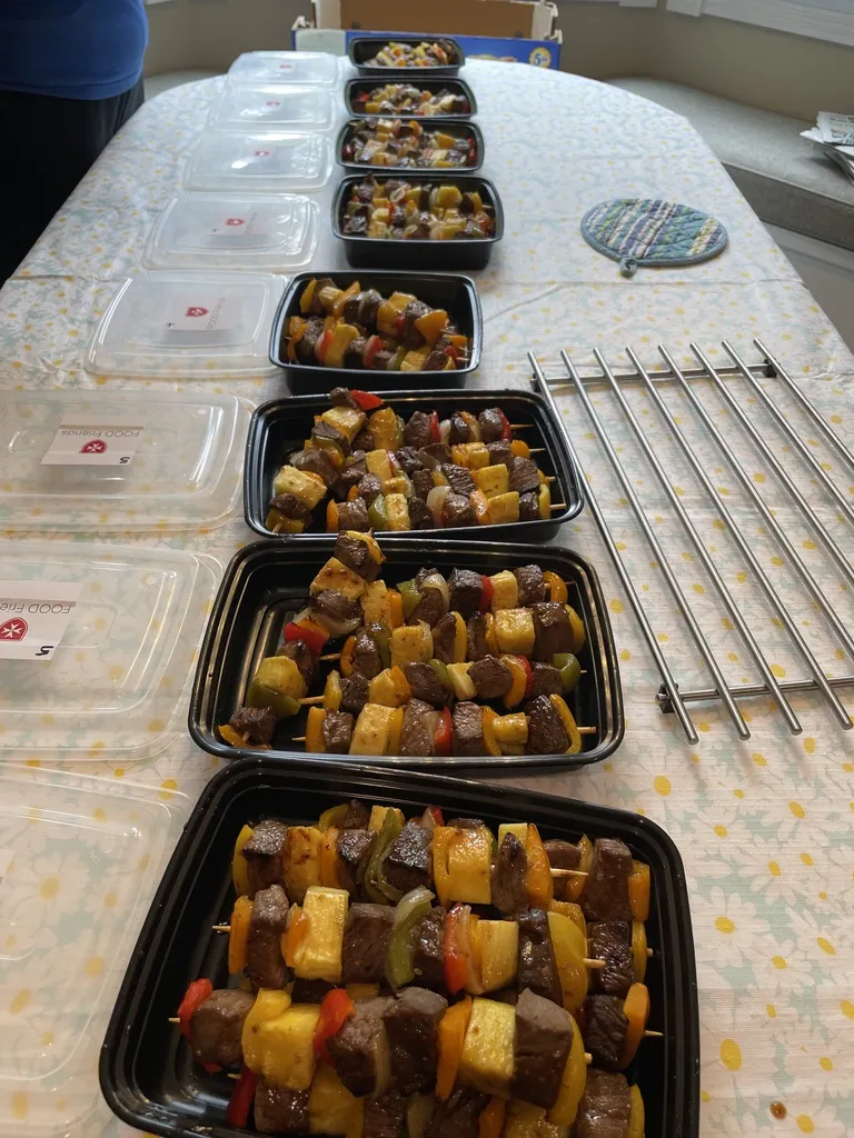 Image of a line of take away containers filled with food ready to be packed up for our Community Dinner for local families.