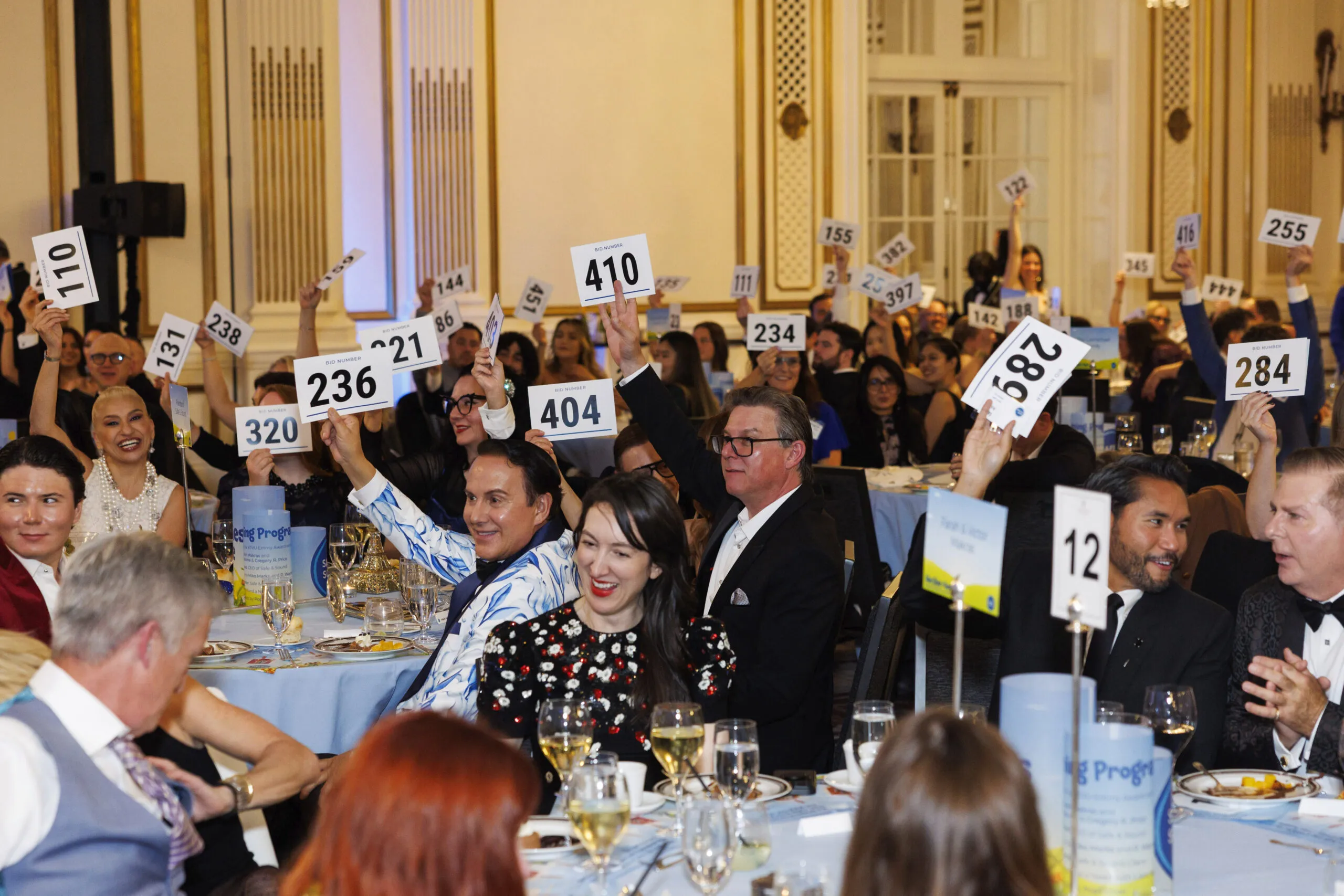 A room of event attendees hold up auction bidding cards