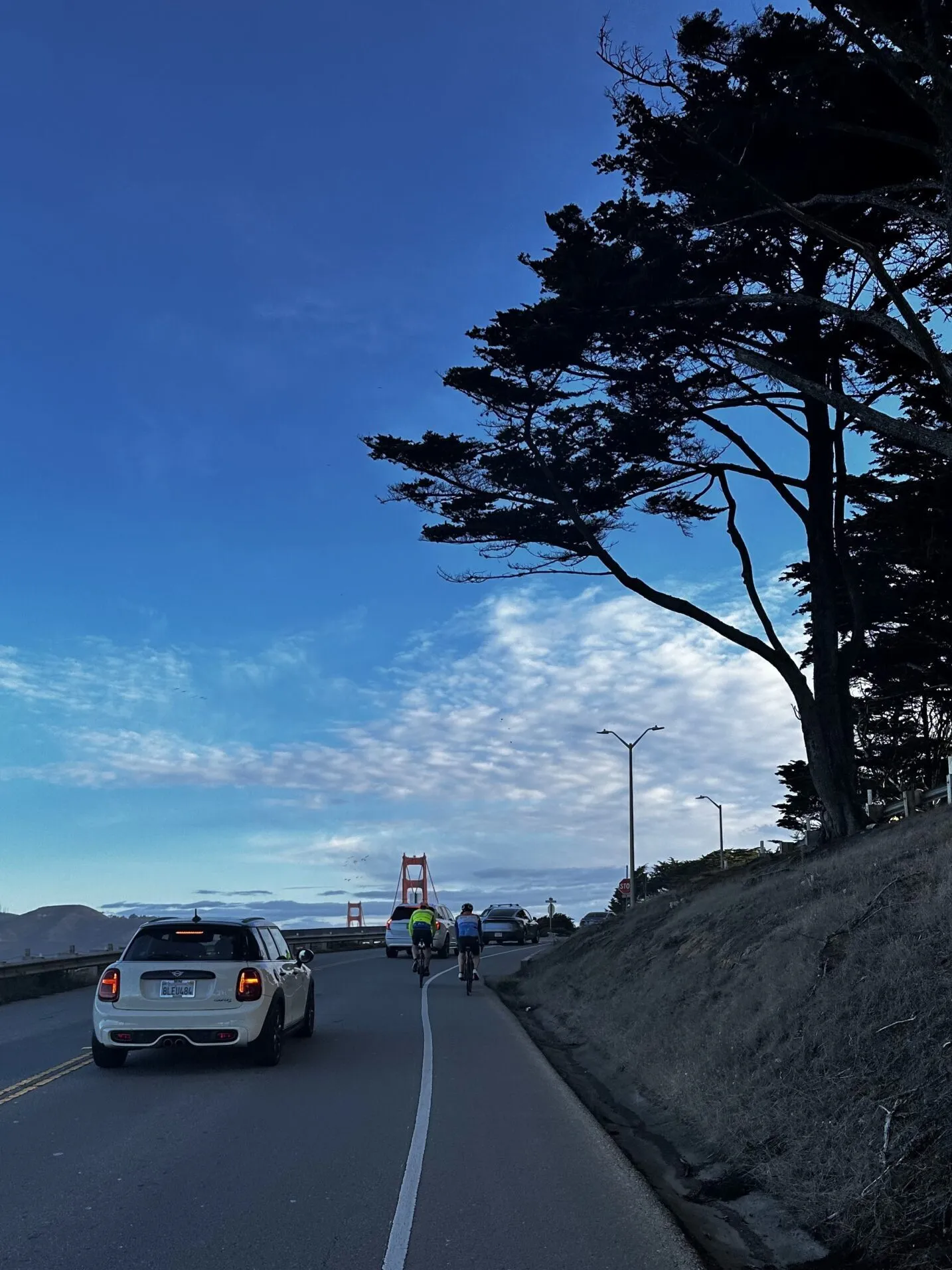 2 people cycle down the road towards the Golden Gate bridge in the distance